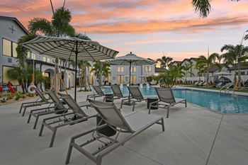 A poolside area with sun loungers and a building in the background.
